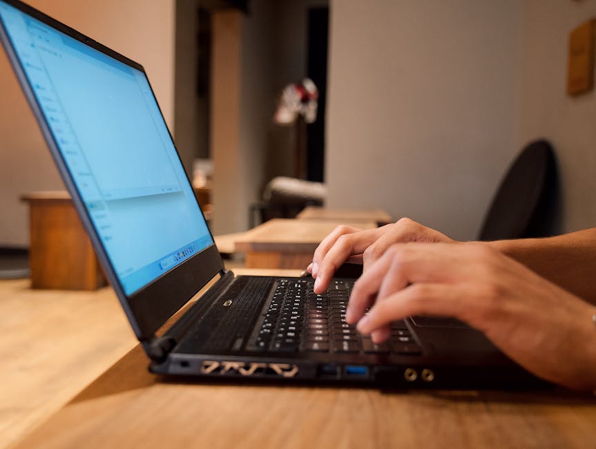 Hands typing on a laptop at a clean modern desk